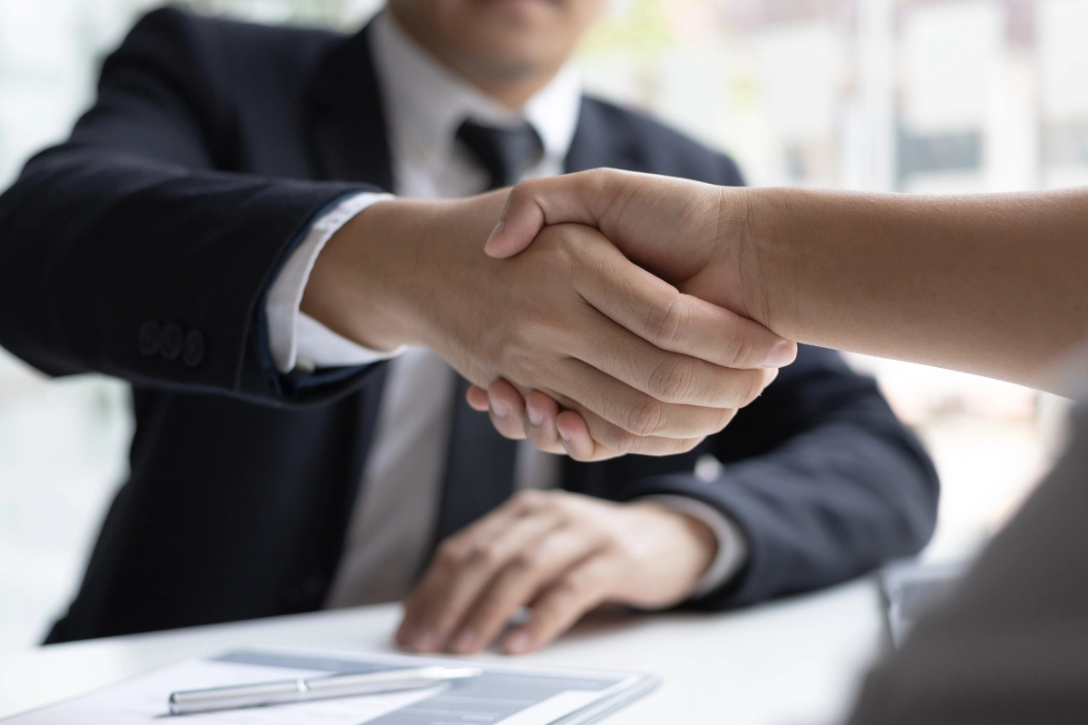 Aperto de mãos formal entre duas pessoas em ambiente de negócios.