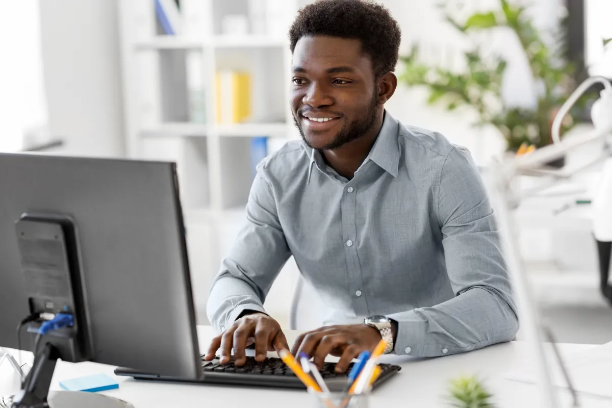 Profissional digitando no computador em ambiente de escritório moderno.