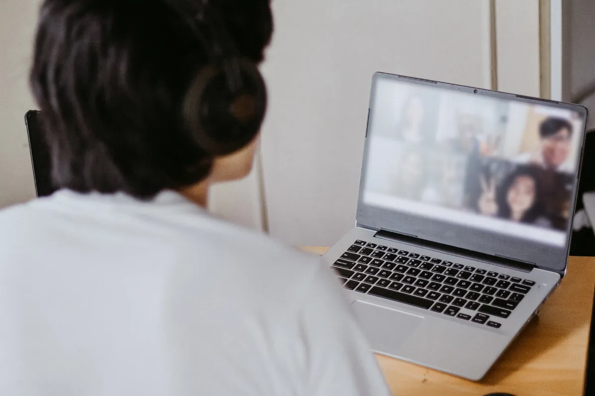 Pessoa participa de videoconferência com grupo de amigos ou colegas usando notebook.