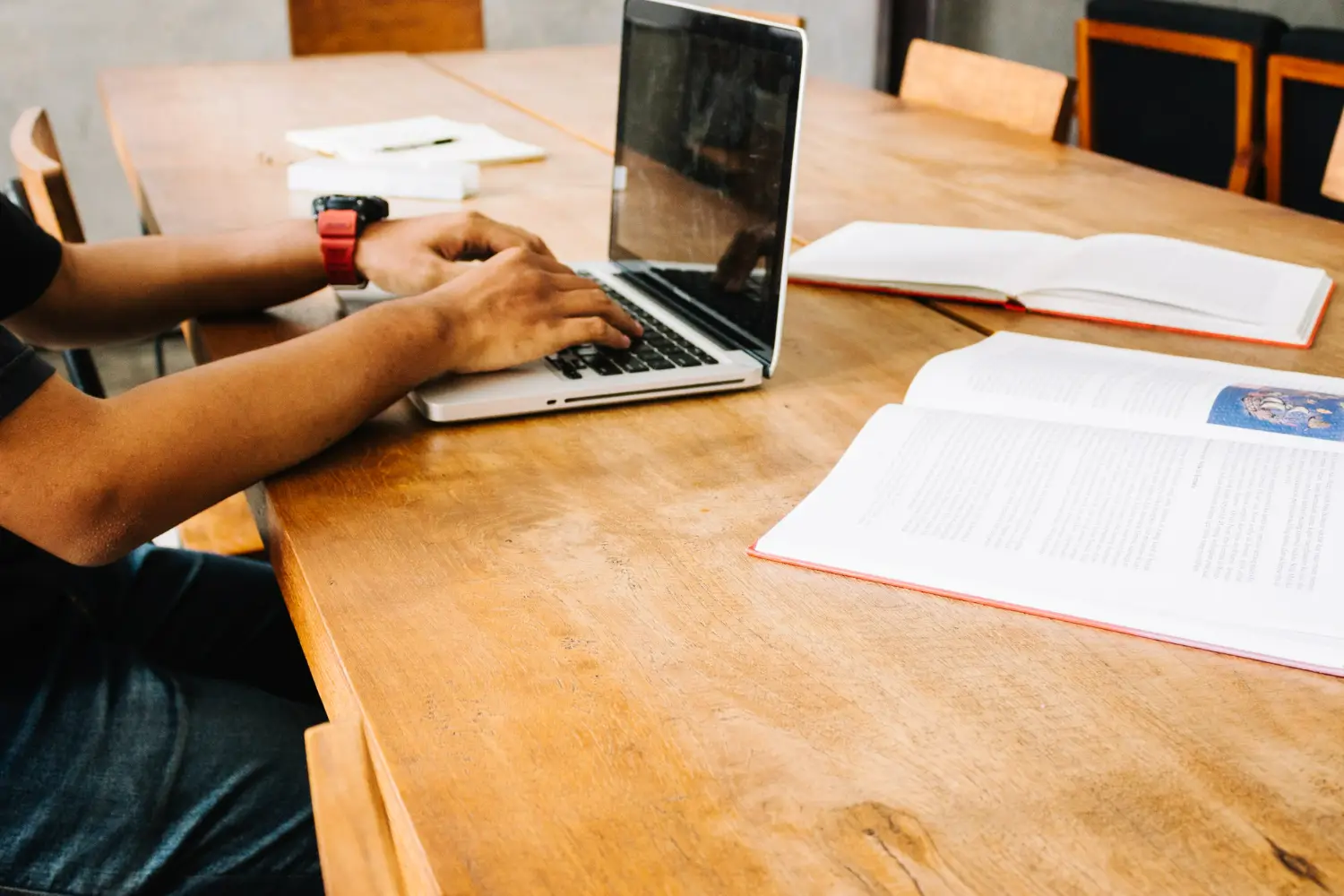 Pessoa utilizando um laptop em uma mesa de estudos com livros abertos, simbolizando a preparação para o processo de inscrição em cursos técnicos.
