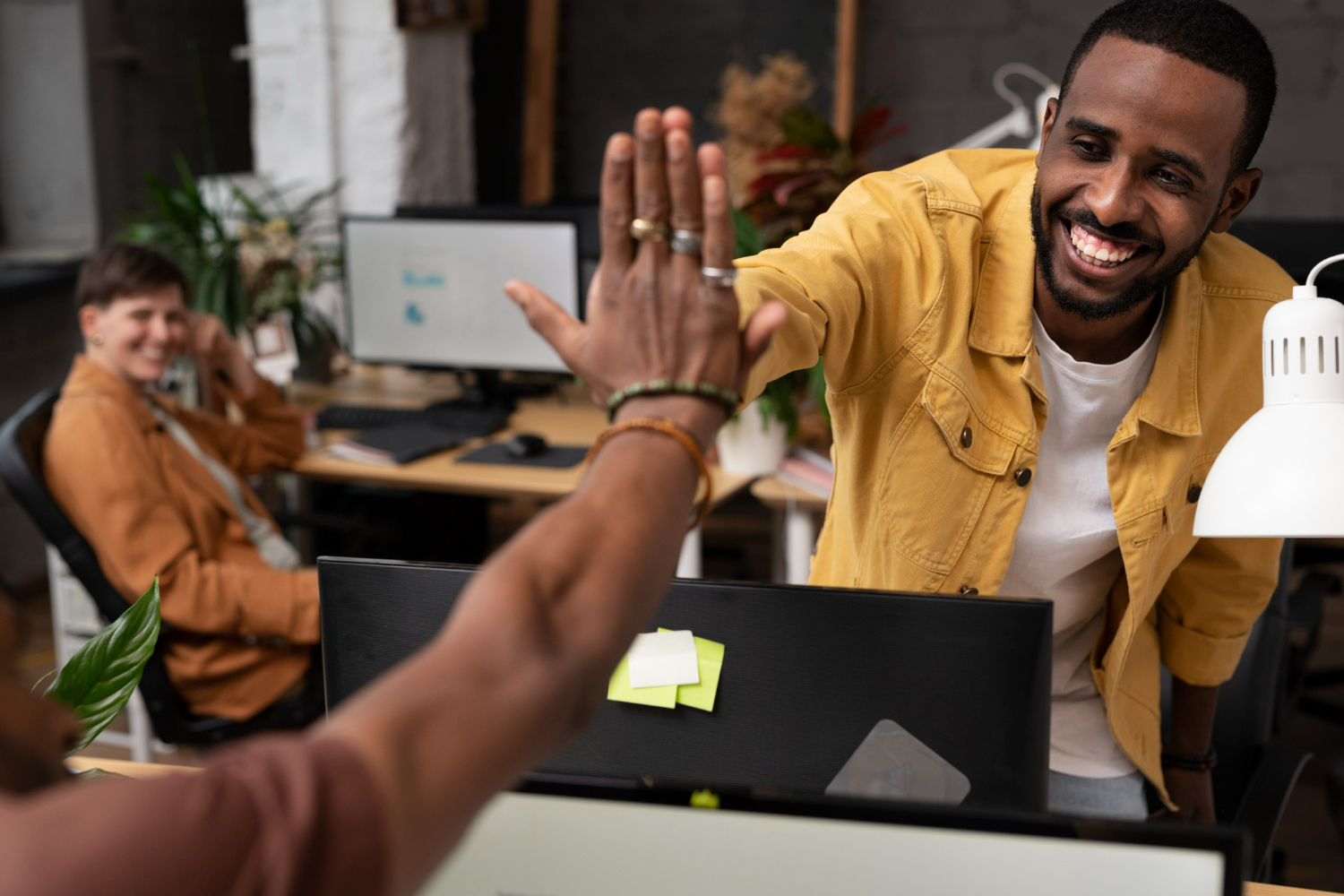 Colegas de trabalho dando um high-five, simbolizando o apoio mútuo e colaboração.