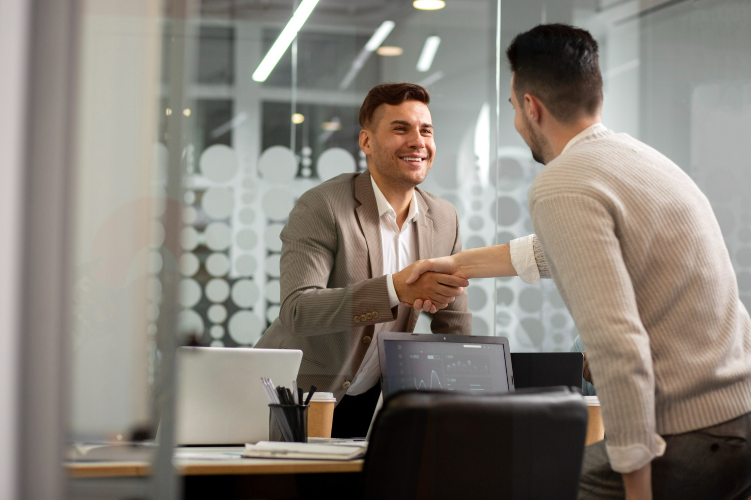Dois profissionais apertando as mãos em um ambiente de escritório moderno, simbolizando a importância do cumprimento de prazos no ambiente de trabalho.
