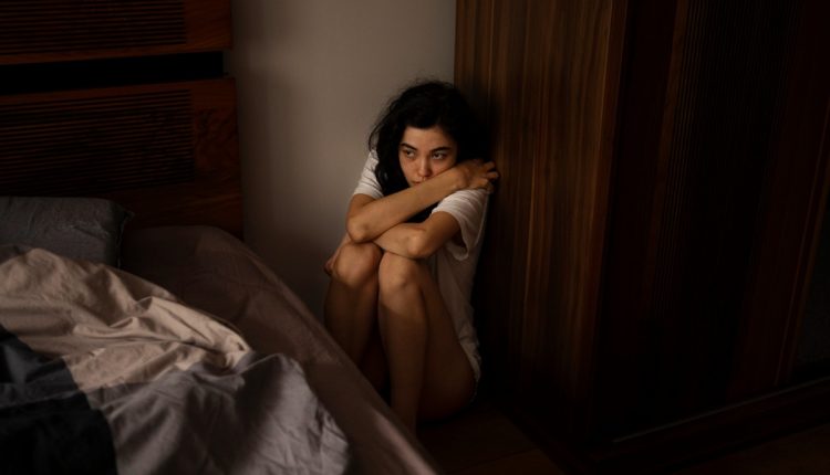 Mulher sentada no chão, representando situação de vulnerabilidade e os benefícios do INSS para vítimas de violência doméstica.