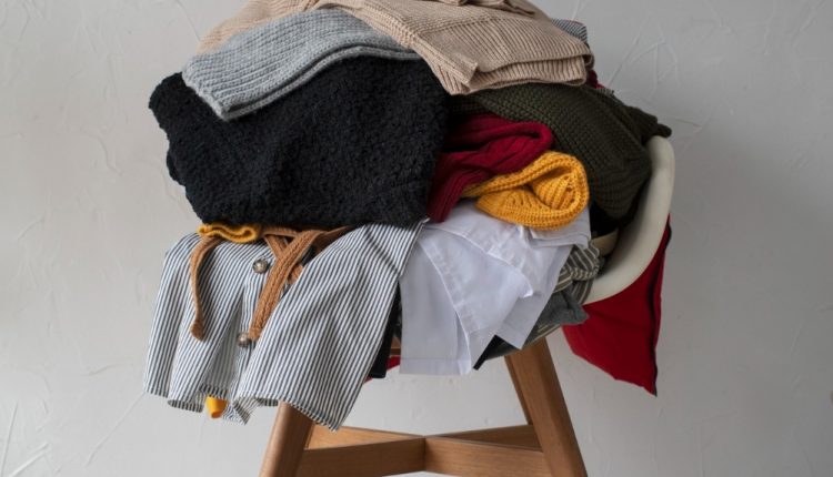 Montanha de roupas empilhadas na cadeira, simbolizando a procrastinação na organização