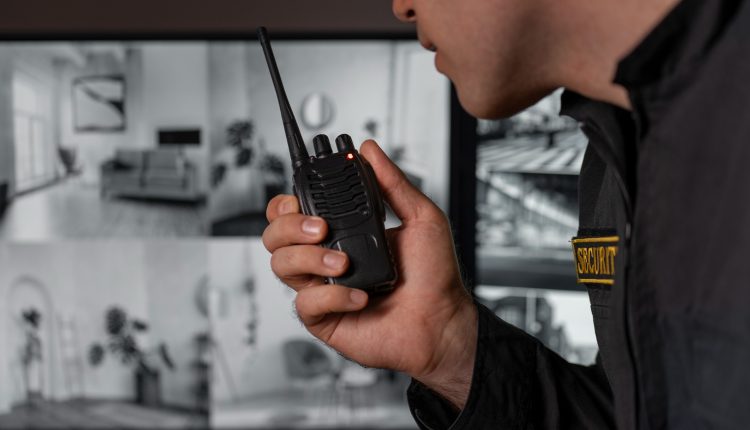 Vigia de segurança monitorando áreas através de rádio e câmeras de segurança, representando o cargo de vigia oferecido no concurso.