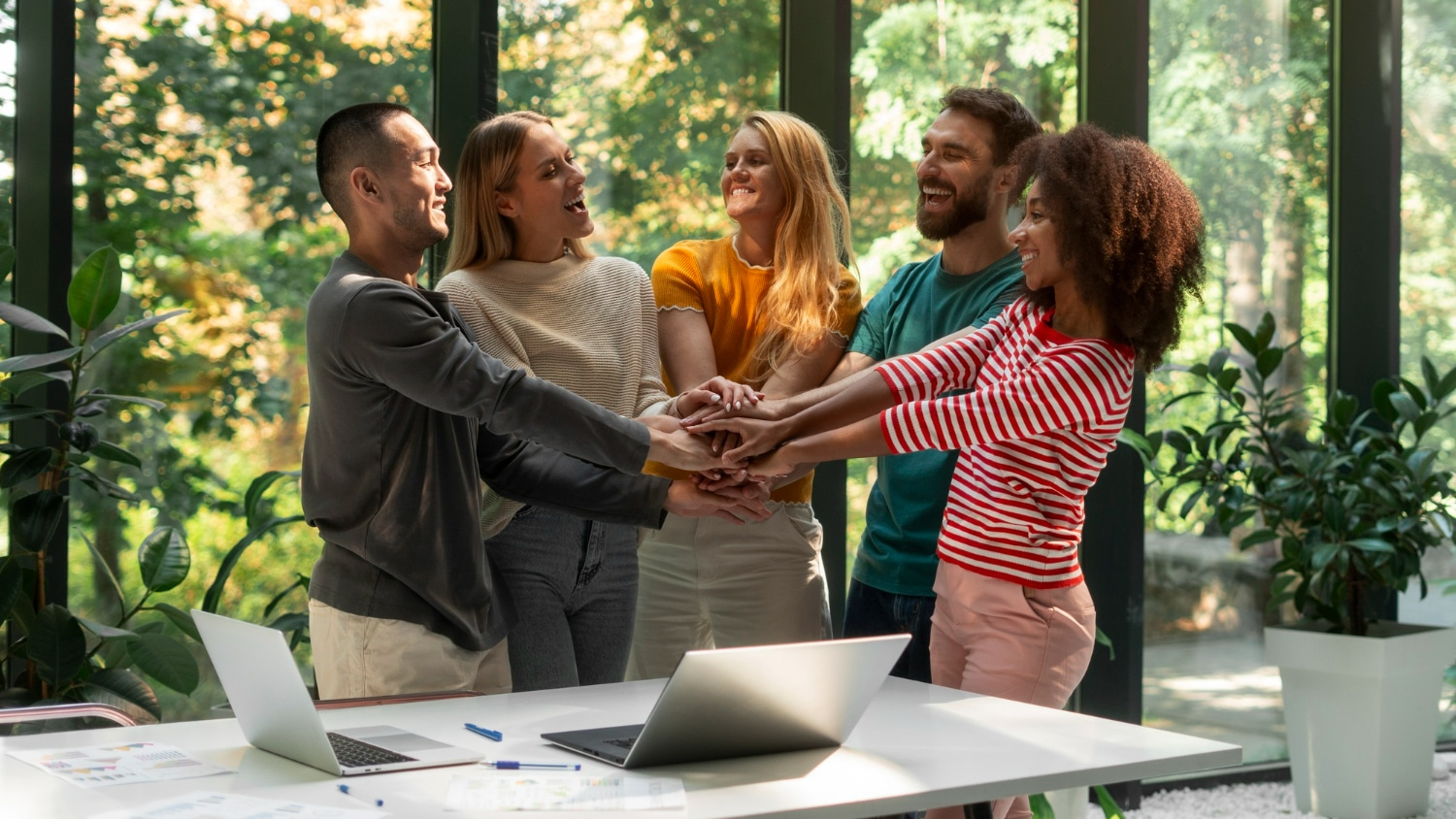 Grupo de pessoas sorrindo e unindo as mãos, simbolizando a colaboração e harmonia nas relações.