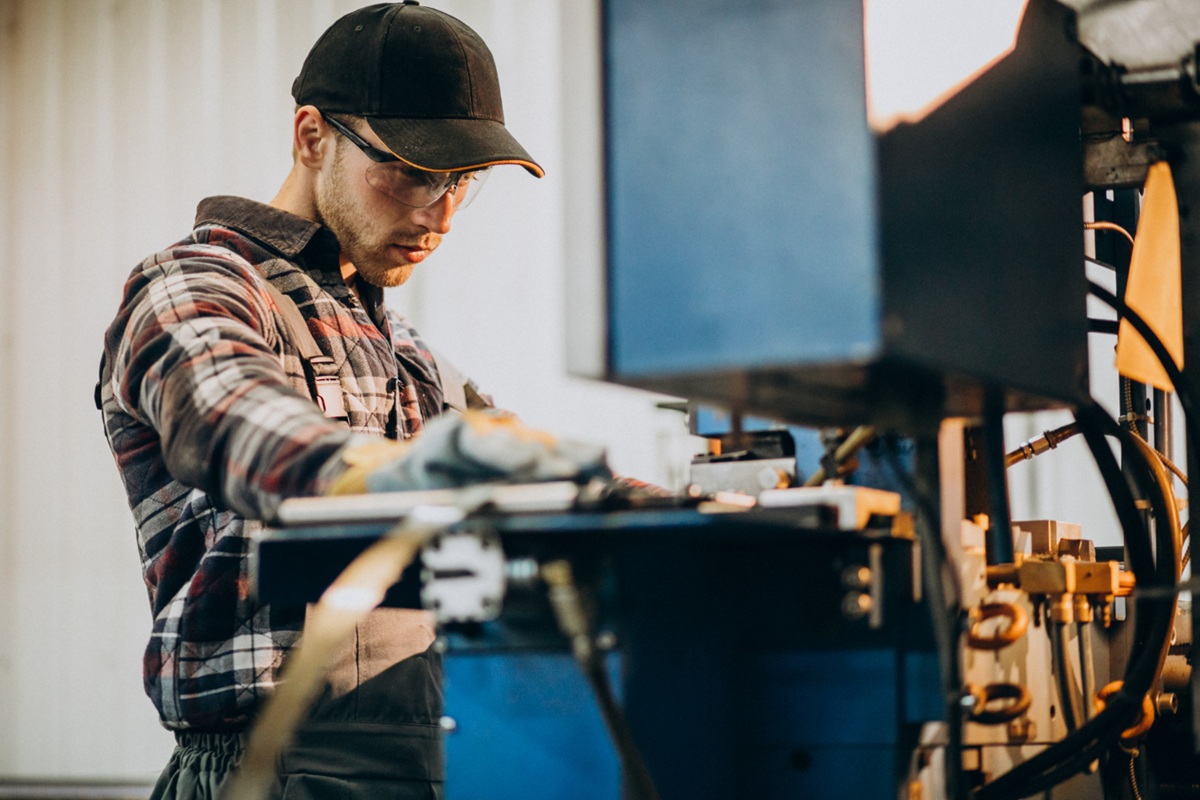 Homem operando uma máquina industrial, simbolizando o trabalho de técnico de manutenção de máquinas.