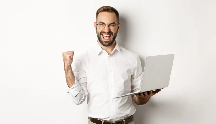 Homem comemorando com laptop, simbolizando o sucesso na carreira de inteligência artificial.