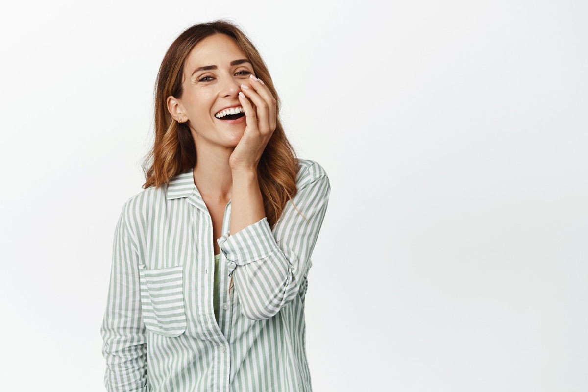 Mulher sorrindo com expressão alegre, ilustrando o papel da psicologia na explicação das crises de riso.