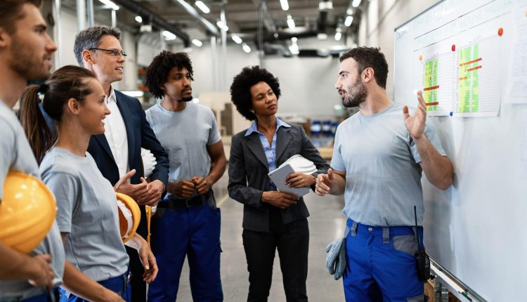 Equipe diversificada discutindo planejamento de segurança e produtividade em ambiente industrial moderno.