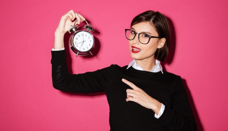 Mulher segurando um relógio despertador vintage com expressão confiante.