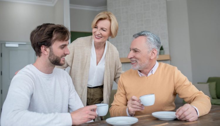 Jovem conversando com casal idoso durante um momento de café.