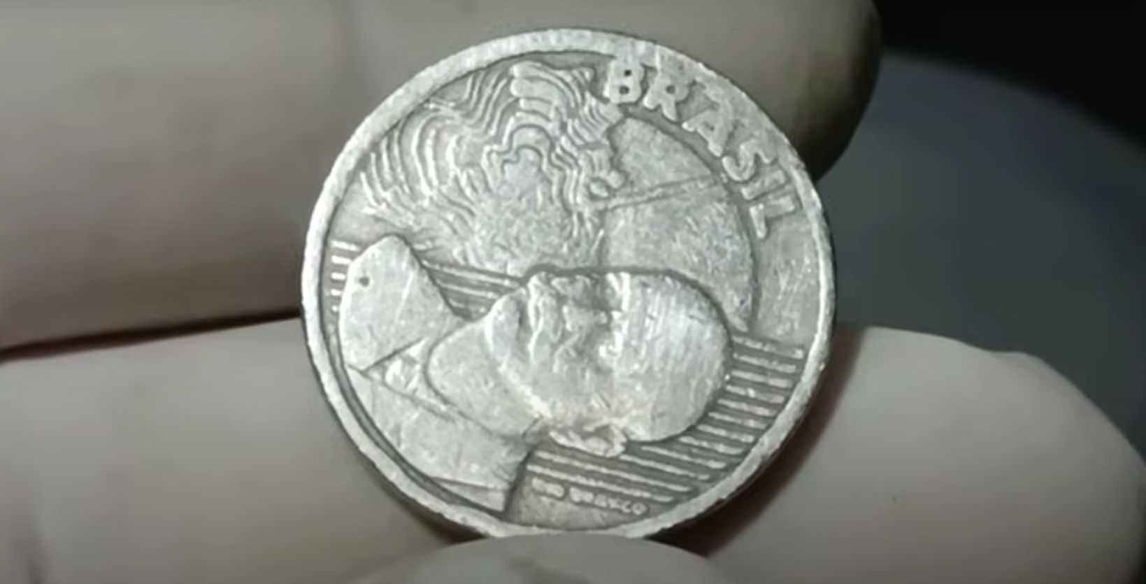 Moeda de 50 centavos com defeito de reverso invertido, visível na face do ex-presidente Juscelino Kubitschek.