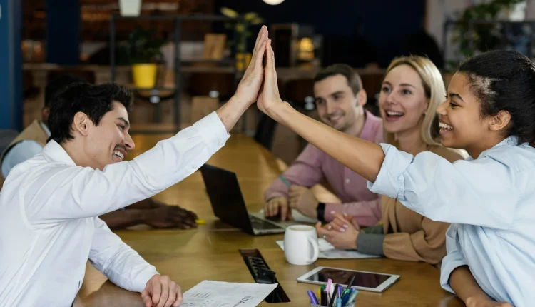 Colaboradores realizando uma comemoração no ambiente de trabalho, com um toque de alta interação e alegria.