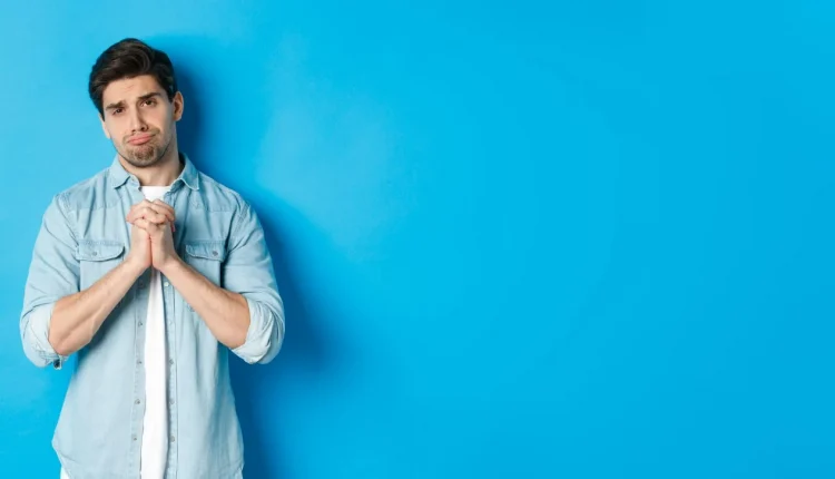Homem com expressão de dúvida, segurando as mãos juntas em frente a um fundo azul claro. A imagem ilustra uma reflexão sobre o plural de palavras em português.