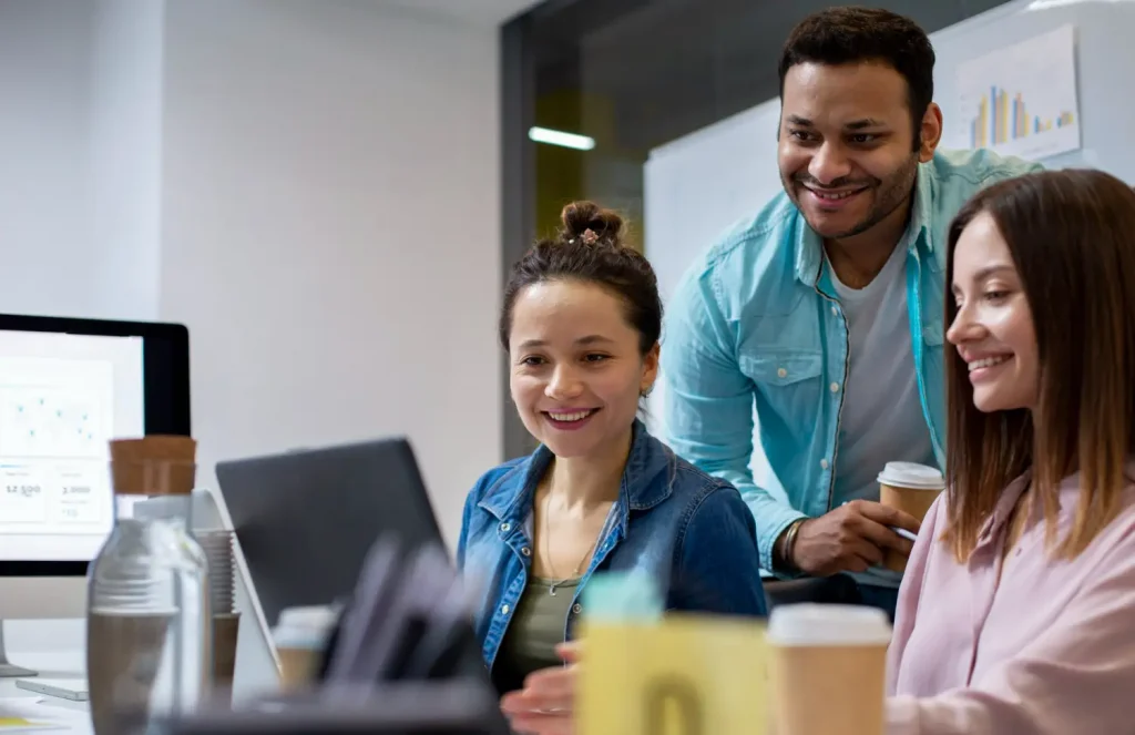 Equipe colaborando em estratégias de marketing com gráficos e laptops, representando o papel do coordenador de marketing.