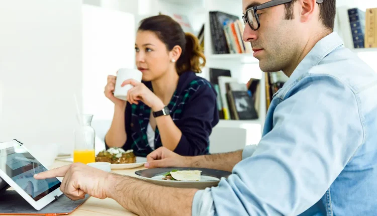 Homem e mulher em um café, trabalhando e explorando informações em um tablet.