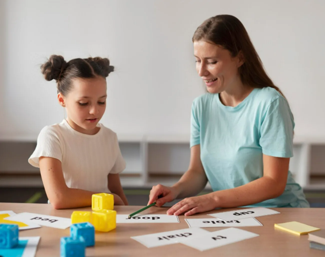 Professora e aluna praticando atividades de memória com blocos educativos e cartões.