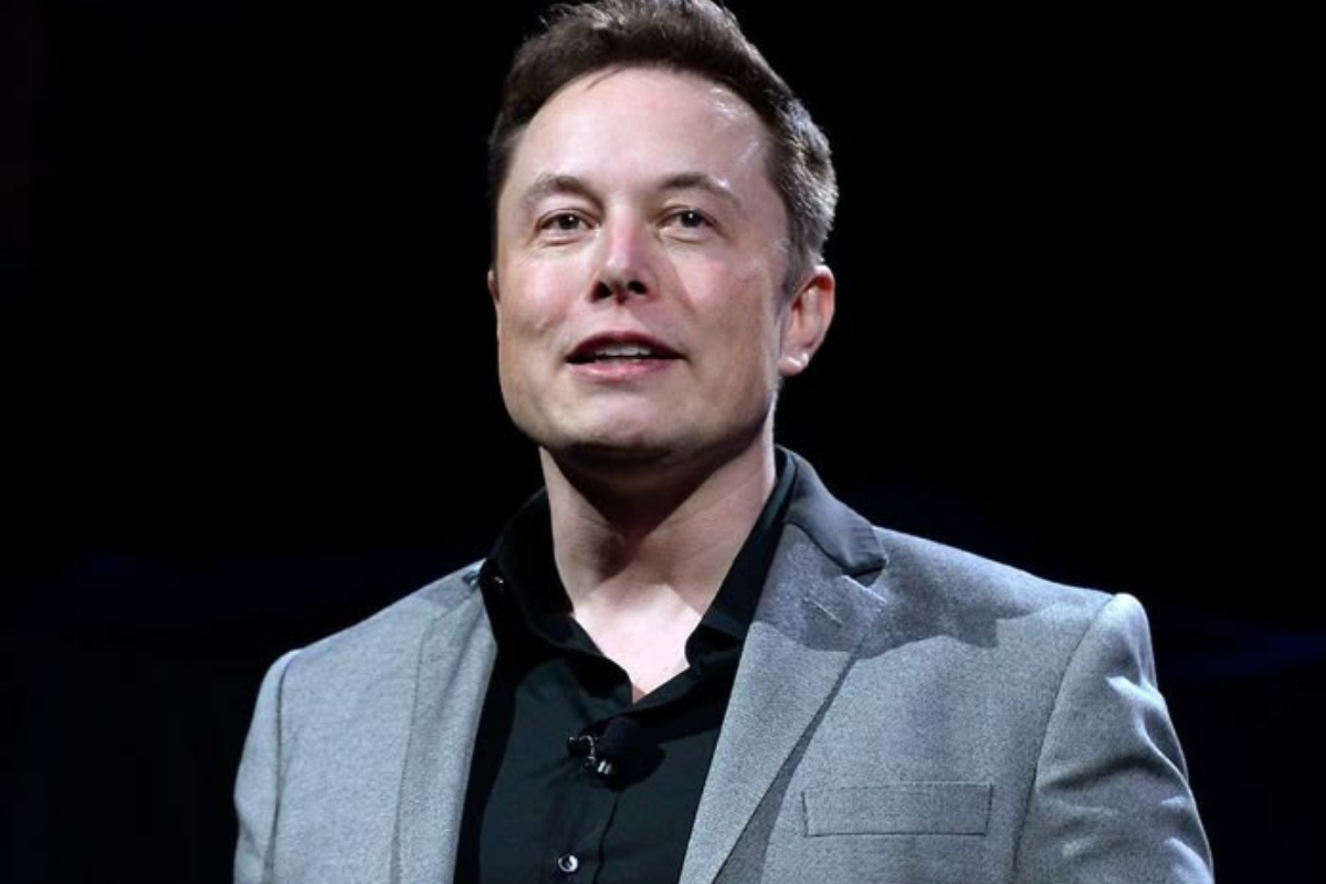 Empreendedor Elon Musk de terno cinza falando em evento de tecnologia.