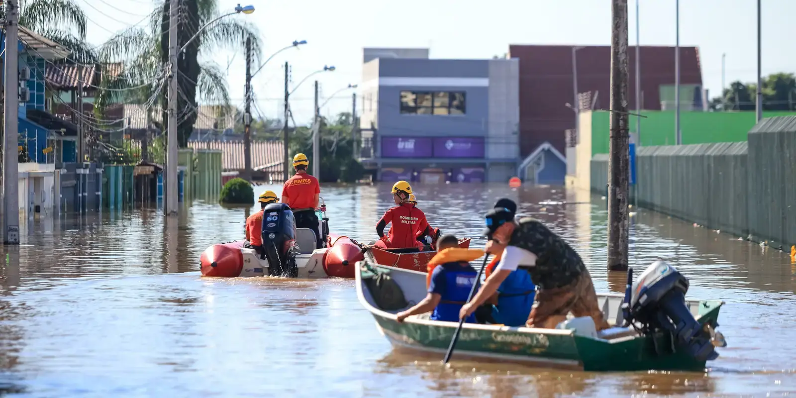 Bombeiros e voluntários resgatam moradores em área alagada após enchente no Rio Grande do Sul.