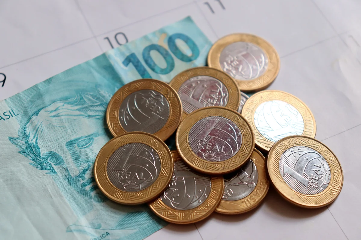 Moedas de 1 real e nota de 100 reais sobre calendário