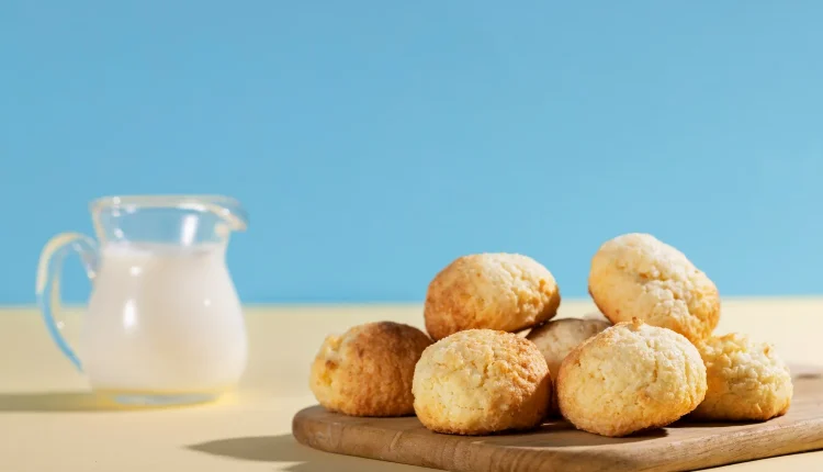 Imagem de pães de queijo frescos, dourados e macios, acompanhados de leite, representando o famoso prato brasileiro.