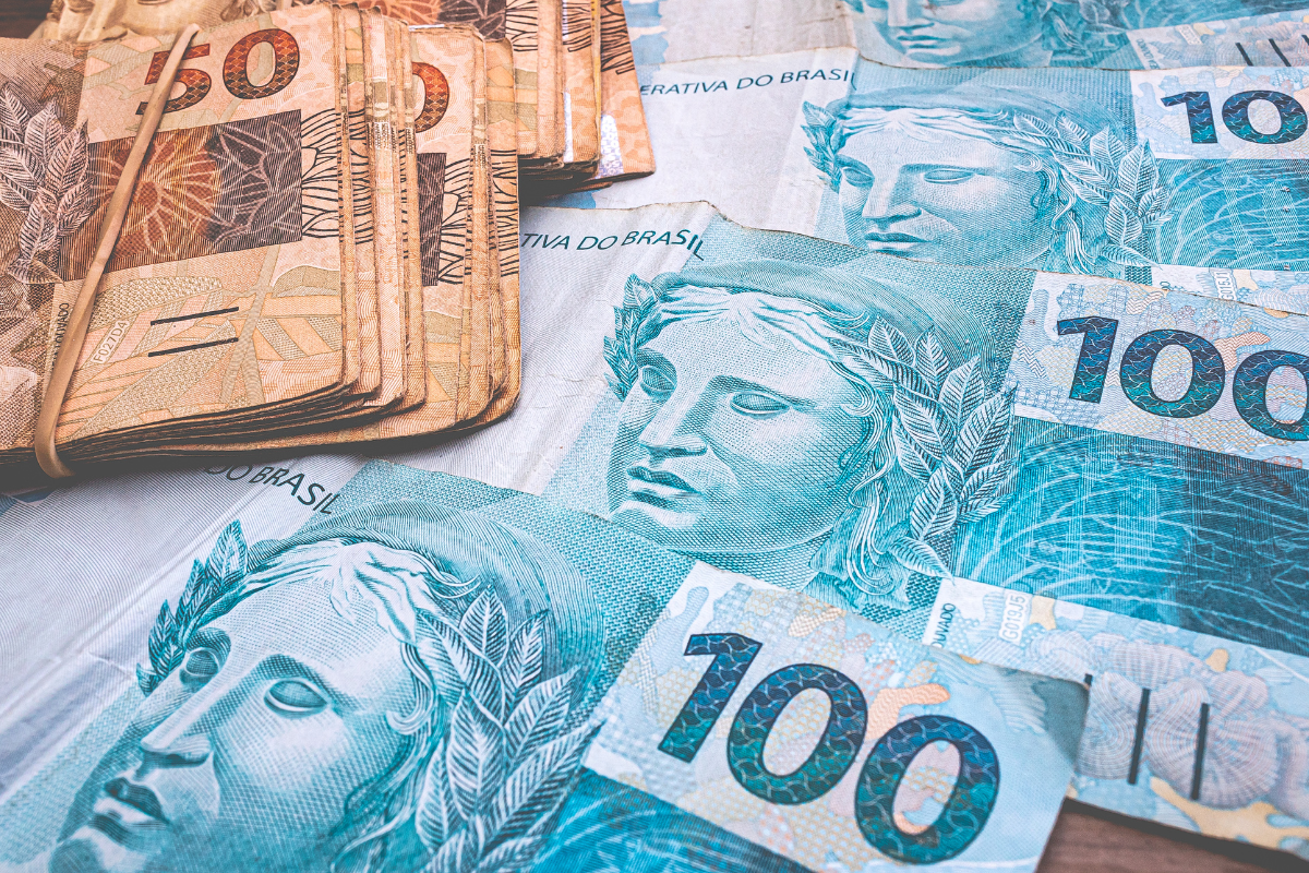 Notas de 50 e 100 reais organizadas sobre uma superfície.