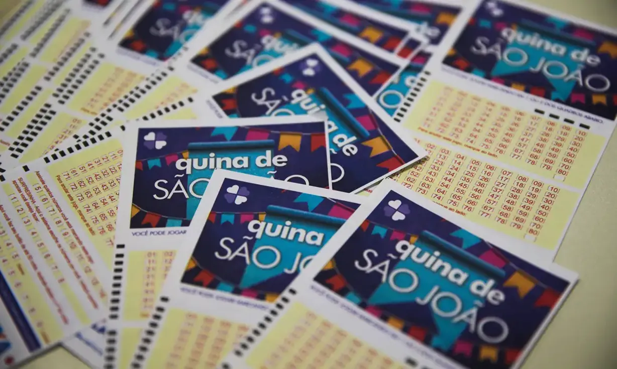 Volantes da Quina de São João espalhados sobre a mesa, prontos para apostas no sorteio de R$ 230 milhões.