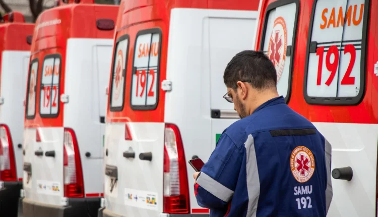 Ambulância do SAMU com profissional de saúde em primeiro plano, trabalhando em uma missão de emergência.