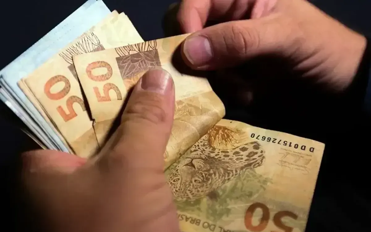 Pessoa contando cédulas de R$ 50