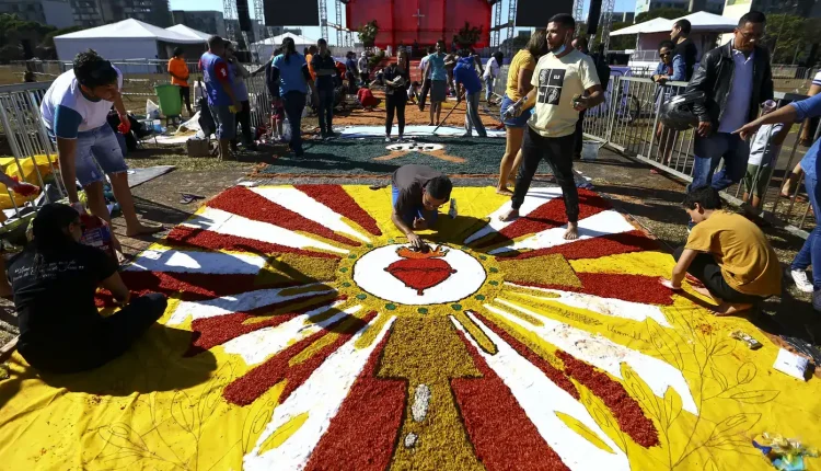 Fiéis montam tapete colorido em celebração ao Corpus Christi em área pública.