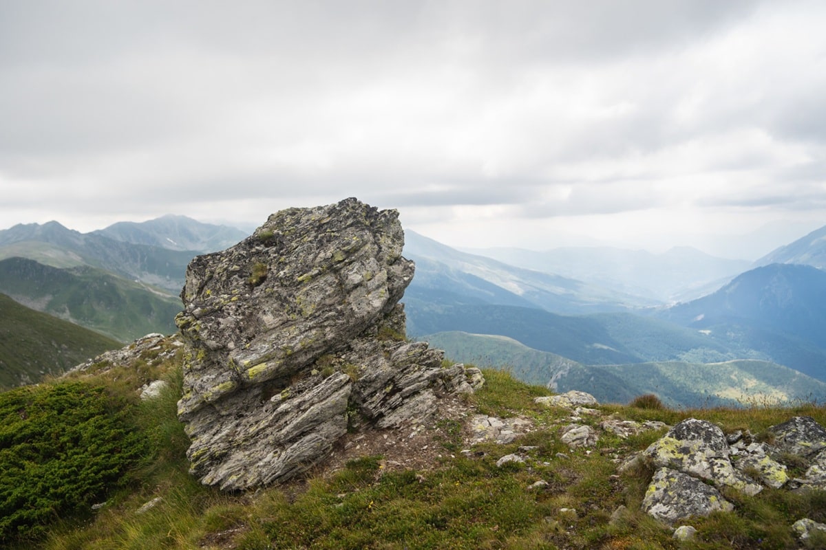 Imagem de uma pedra gigante em uma paisagem montanhosa, representando o aumentativo de 'pedra'.