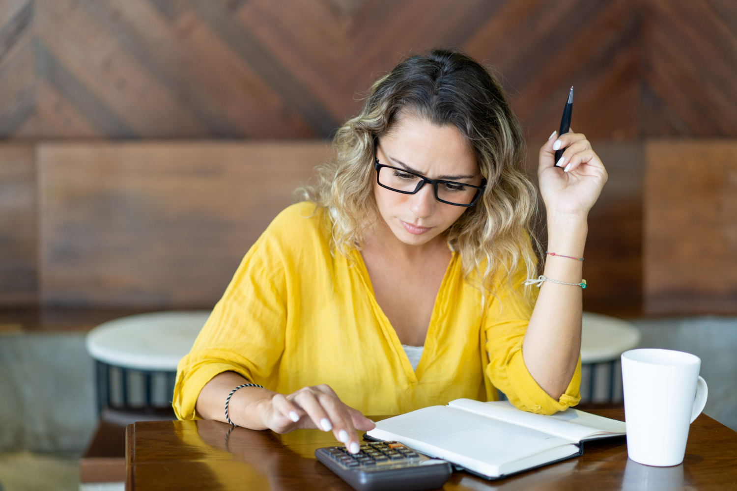 Mulher calculando com calculadora e analisando números, ilustrando o cálculo de classe social com base em dependentes.