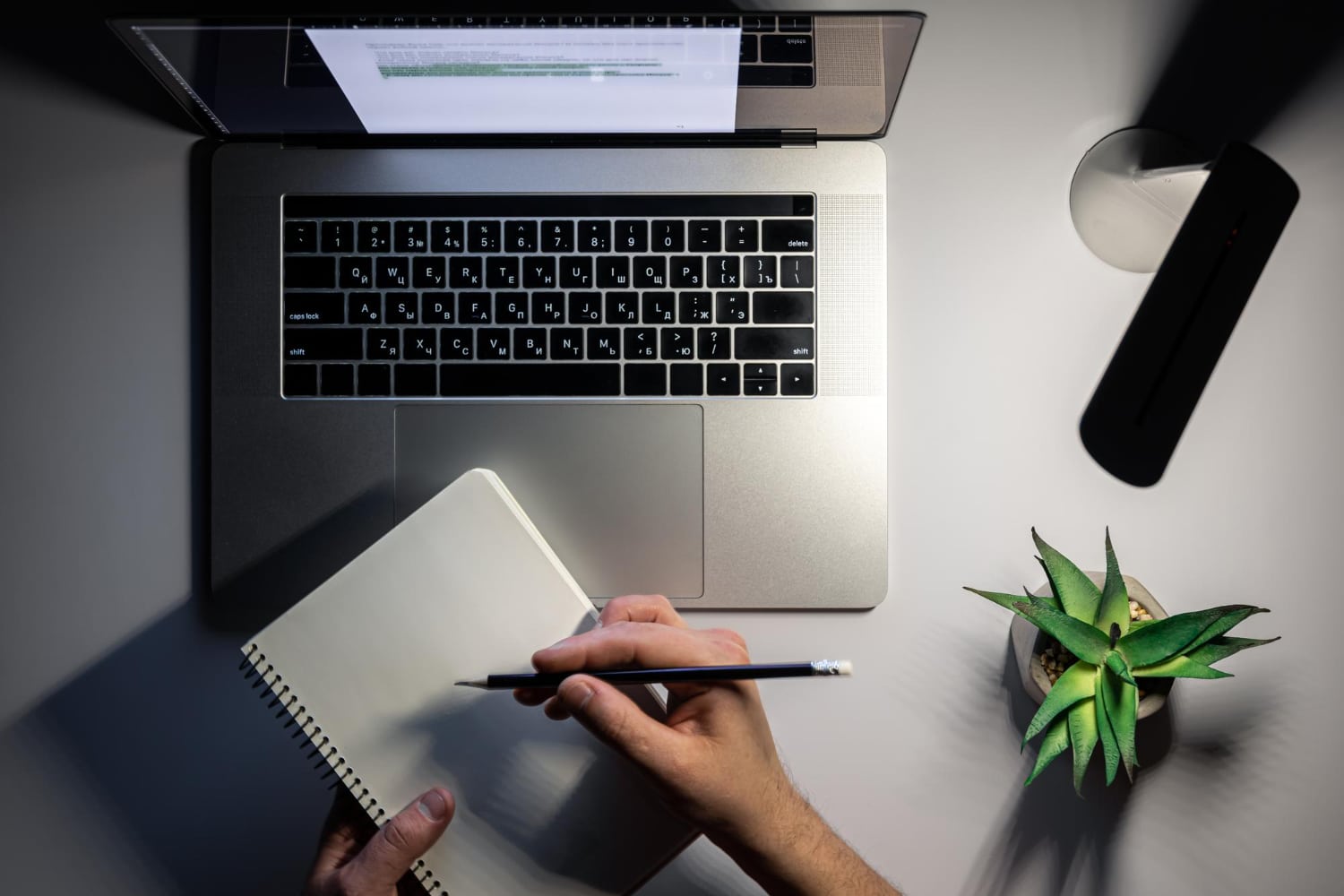 Pessoa estudando com um notebook e caderno, simbolizando a preparação para provas e atualidades.