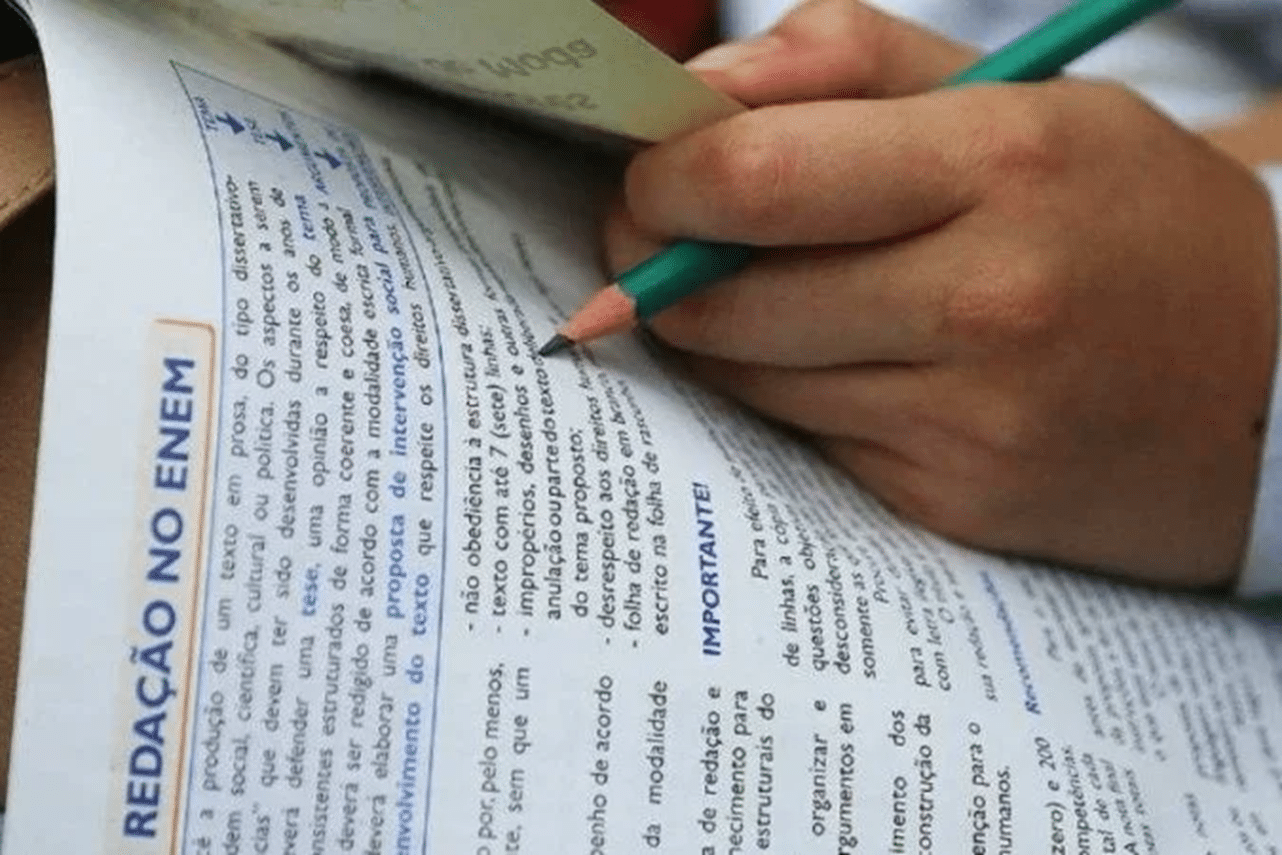 Pessoa revisando um material sobre redação do Enem, com destaque para a parte que aborda as regras da competência 1.