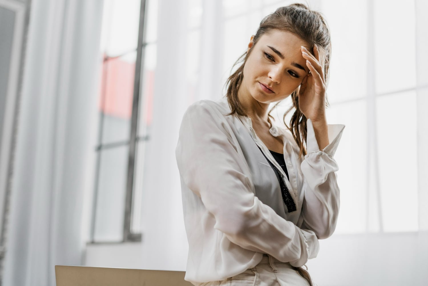 Mulher com expressão de preocupação, refletindo sobre um pensamento negativo e a manifestação do pessimismo excessivo.