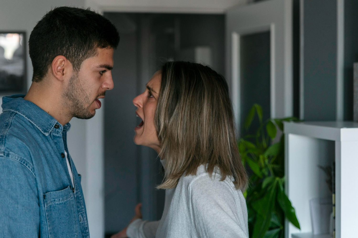 Casal discutindo em casa, ambos com expressões de raiva e frustração.