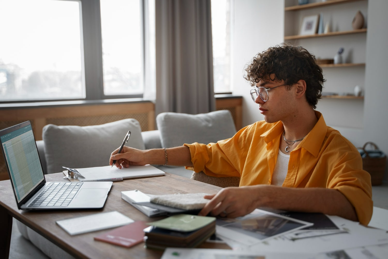 Jovem estudando com laptop, caderno e materiais de estudo, representando o processo de aprendizado para o Enem 2025.