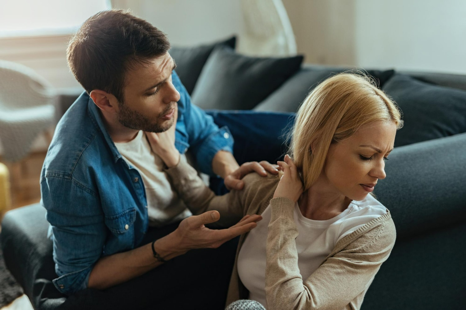 Homem tentando falar com mulher desconfortável e evitativa durante uma discussão.
