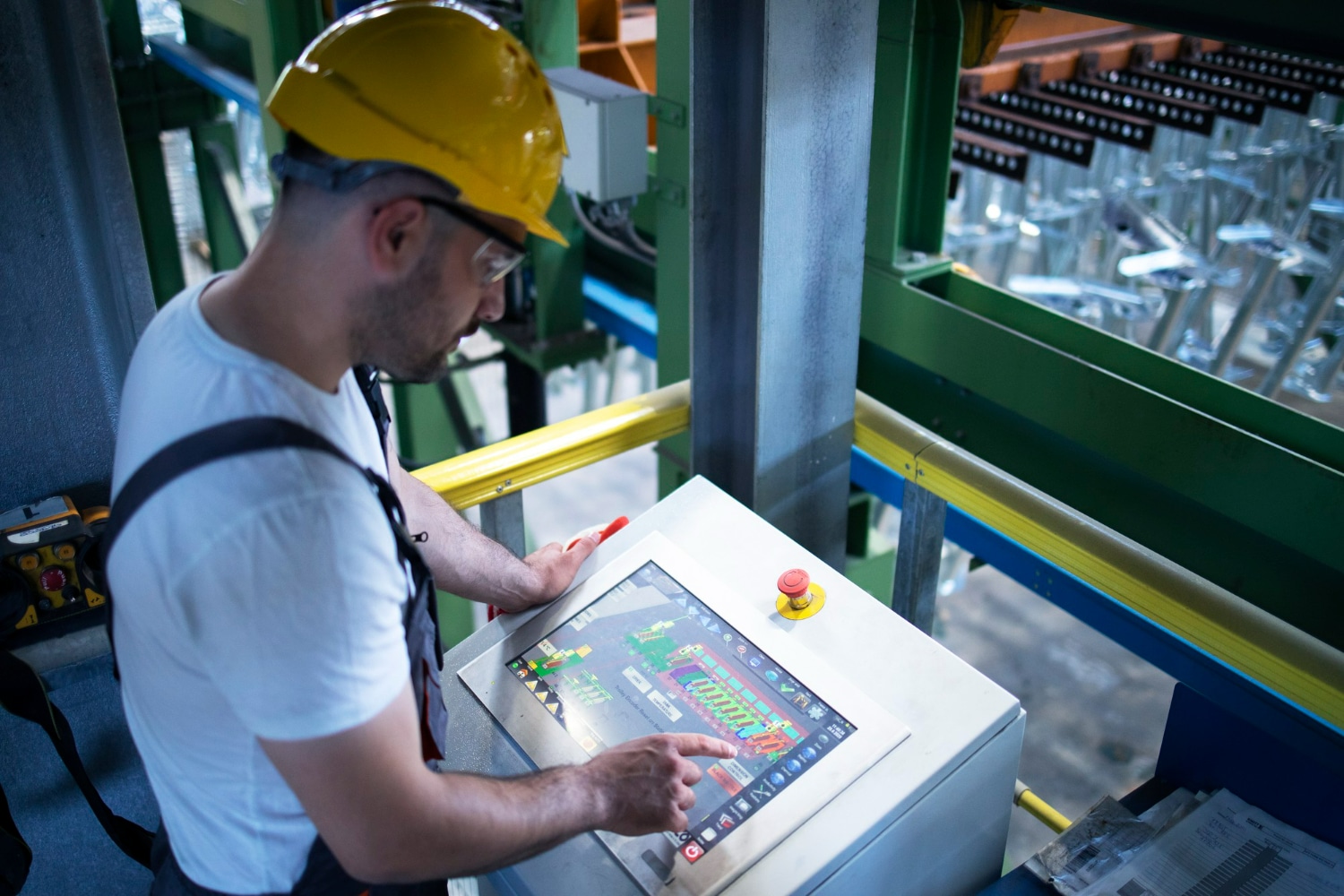 Técnico em automação industrial operando painel de controle de sistema automatizado em uma fábrica.