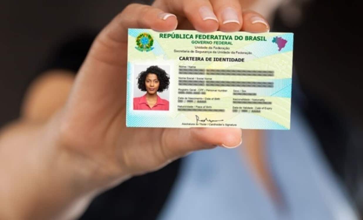 Pessoa segurando a nova Carteira de Identidade Nacional (CIN), exemplificando o novo formato do RG com foto, QR Code e dados oficiais.