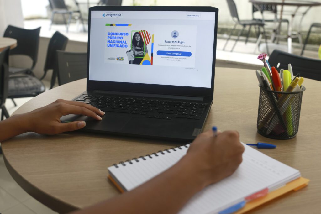 Pessoa se prepara para o Concurso Nacional Unificado acessando a plataforma de inscrição no notebook