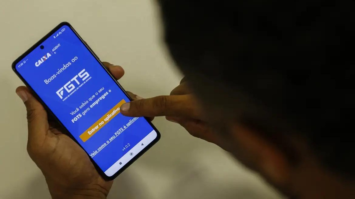 Pessoa acessando aplicativo do FGTS no celular para consultar pagamento de lucro.