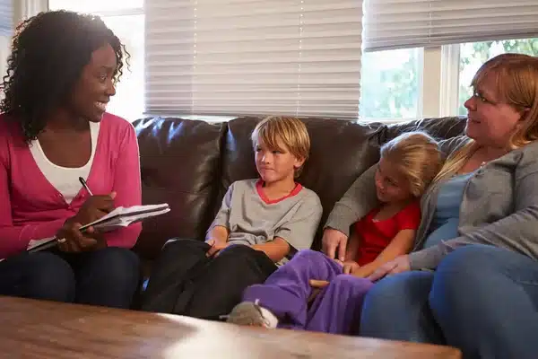 Assistente social conversando com uma mãe e crianças durante atendimento familiar