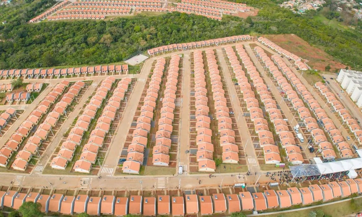 Vista aérea de conjunto habitacional com casas populares organizadas em fileiras.