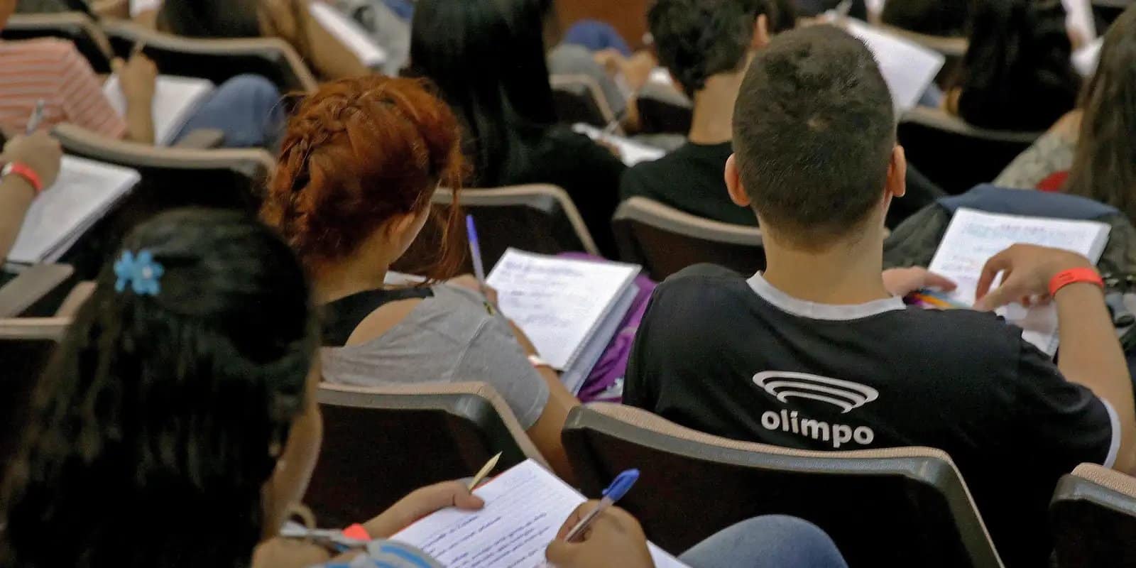 Estudantes escrevendo em cadernos durante aula preparatória para o Enem.