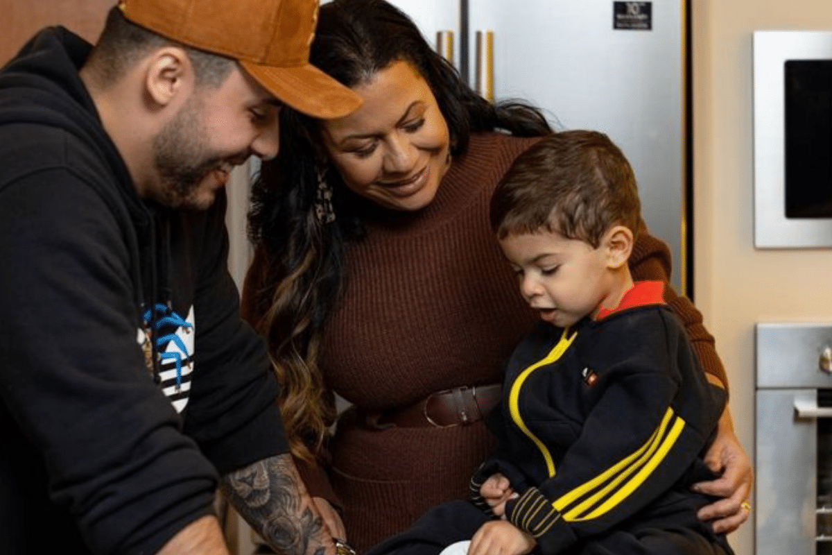 Pai, mãe e filho pequeno interagindo juntos em ambiente familiar.