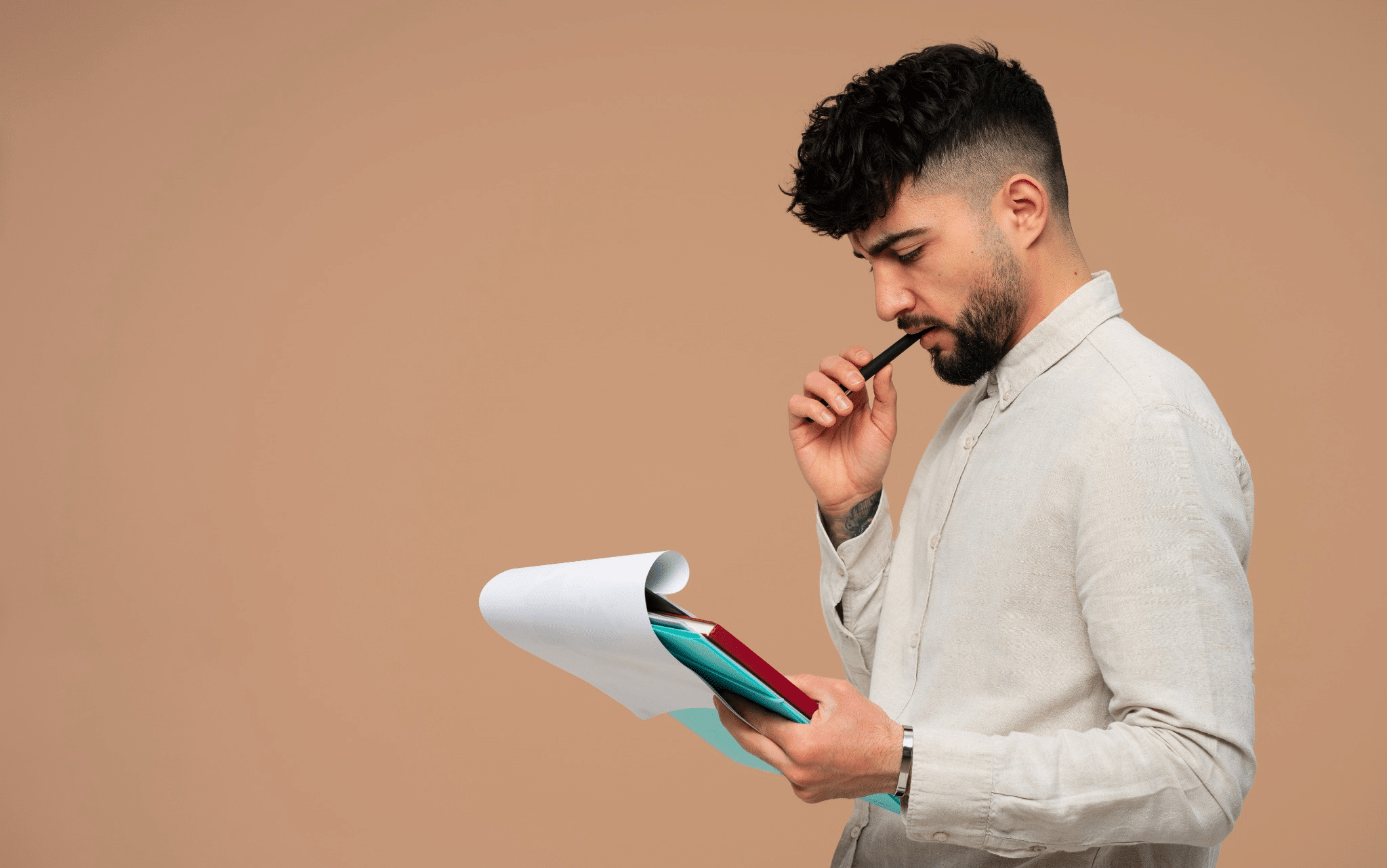 Homem jovem analisando documentos com expressão de concentração.