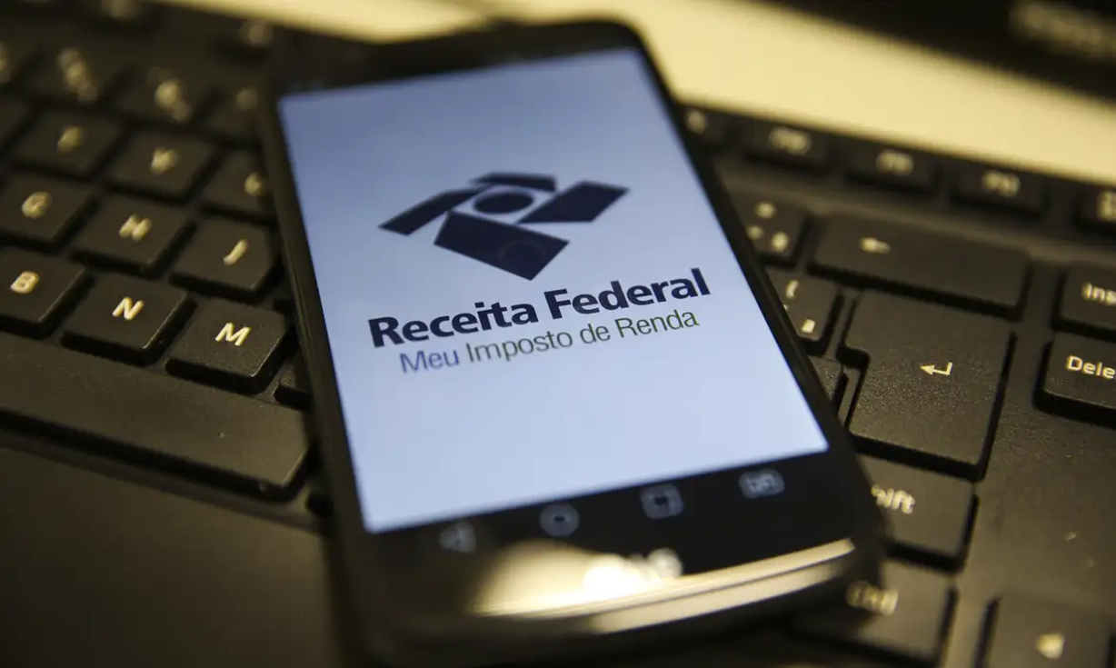 Logo da Receita Federal com o aplicativo Meu Imposto de Renda sobre teclado.