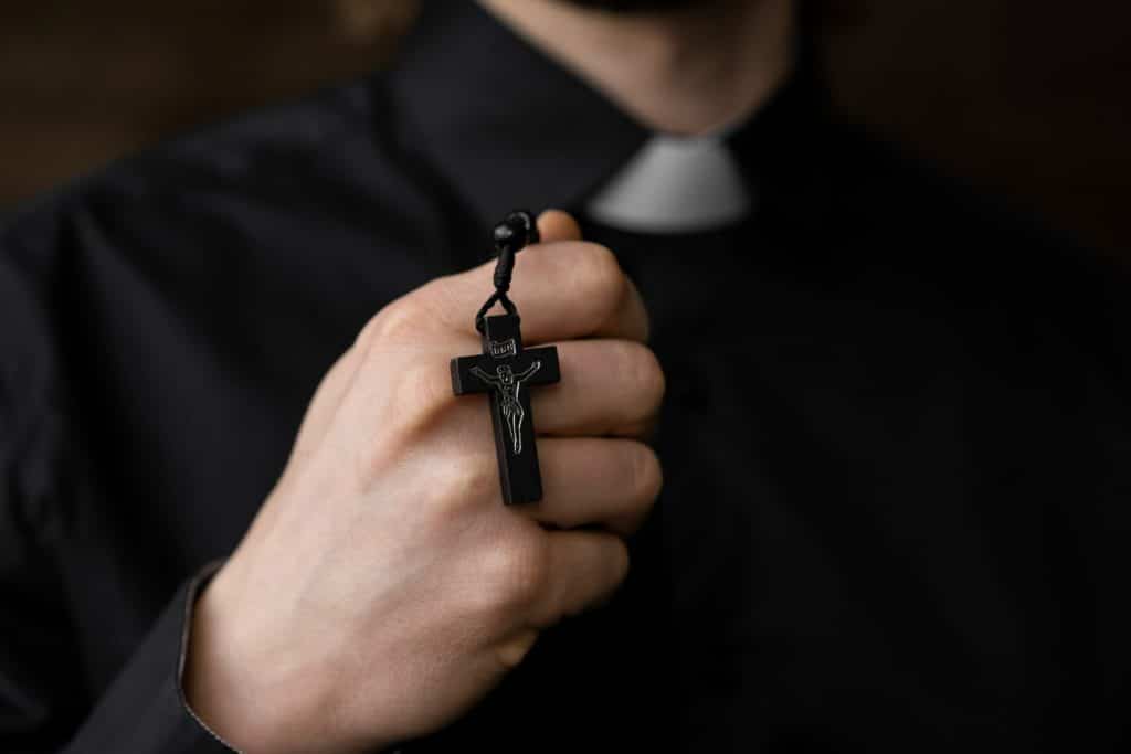 Imagem de um sacerdote segurando um crucifixo de São Miguel Arcanjo.
